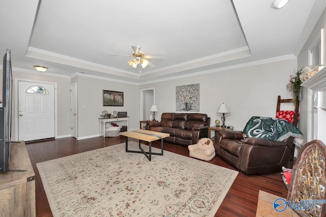 living room featuring ornamental molding, dark wood-type flooring, and a raised ceiling