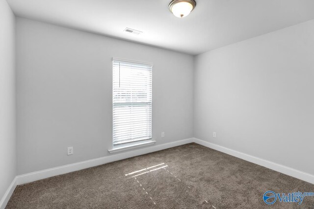 empty room with carpet flooring, visible vents, and baseboards