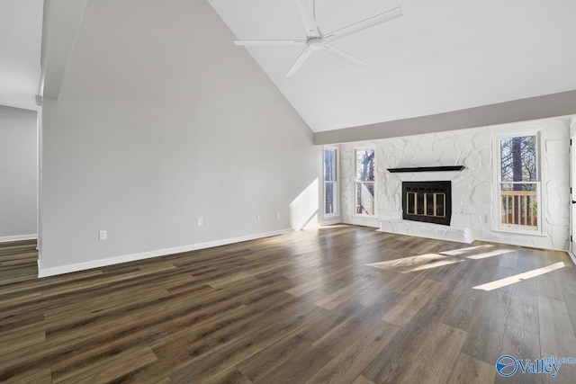 unfurnished living room featuring a stone fireplace, ceiling fan, high vaulted ceiling, and dark wood-type flooring