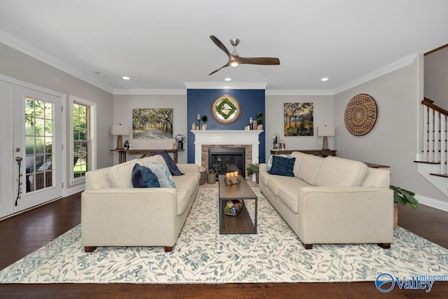 living room with ornamental molding, a glass covered fireplace, stairway, and wood finished floors