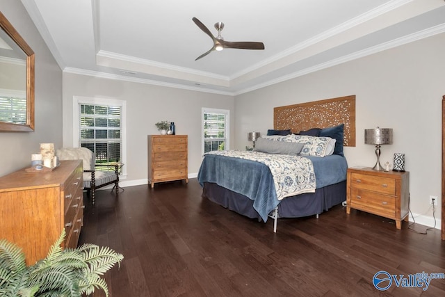 bedroom featuring dark wood-style flooring, a raised ceiling, crown molding, and baseboards