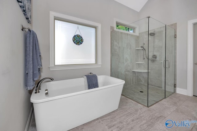 bathroom with a stall shower, a freestanding bath, and baseboards