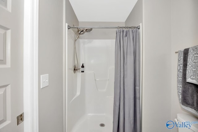 full bathroom with toilet and a shower with shower curtain