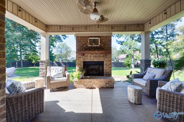 view of patio / terrace featuring an outdoor brick fireplace, fence, and a ceiling fan