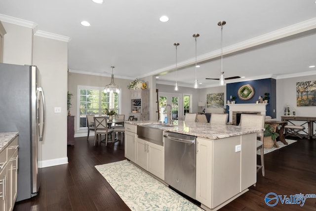 kitchen featuring dark wood-type flooring, a fireplace, a sink, appliances with stainless steel finishes, and an island with sink