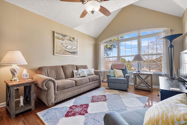 living area featuring ceiling fan, baseboards, hardwood / wood-style floors, vaulted ceiling, and a textured ceiling