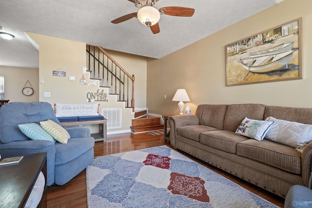 living room featuring visible vents, a textured ceiling, wood finished floors, stairway, and ceiling fan