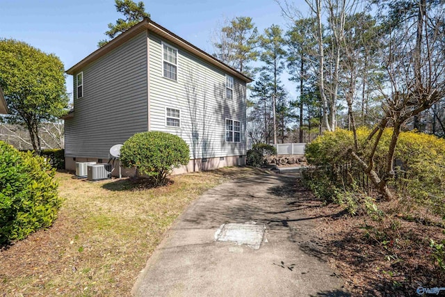 view of home's exterior with cooling unit, a yard, and driveway