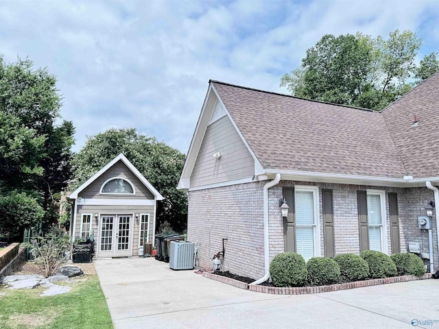 3205 Germantown Pl, Decatur, AL 35603 - view of property exterior featuring french doors, roof with shingles, brick siding, and central AC unit