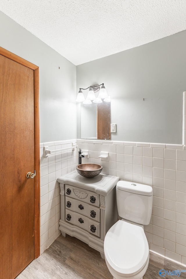 bathroom with vanity, hardwood / wood-style flooring, toilet, tile walls, and a textured ceiling