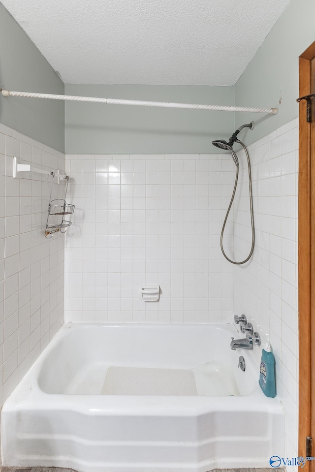 bathroom featuring tiled shower / bath combo and a textured ceiling