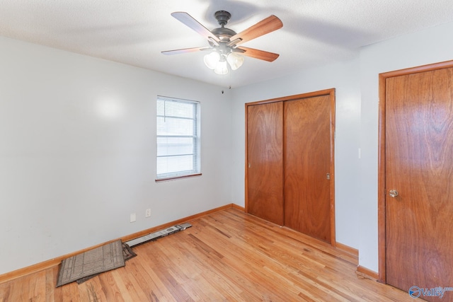 unfurnished bedroom with ceiling fan, light wood-type flooring, a textured ceiling, and a closet