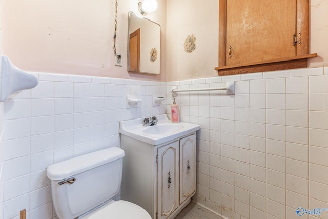 bathroom featuring vanity, toilet, and tile walls