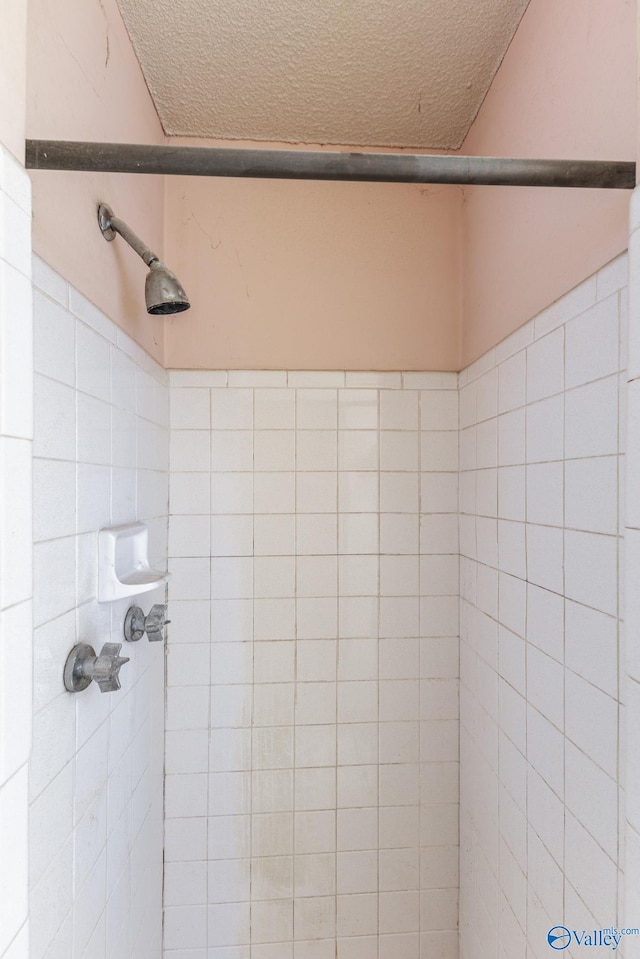 bathroom with tiled shower and a textured ceiling