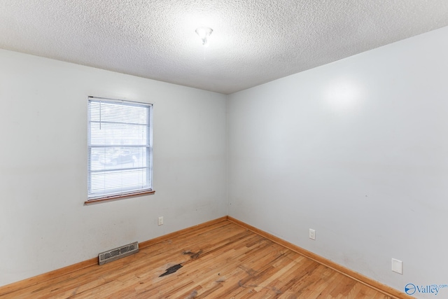 spare room with a textured ceiling and hardwood / wood-style flooring