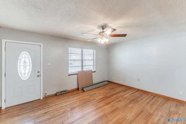 foyer featuring ceiling fan, light hardwood / wood-style floors, a textured ceiling, and a baseboard heating unit