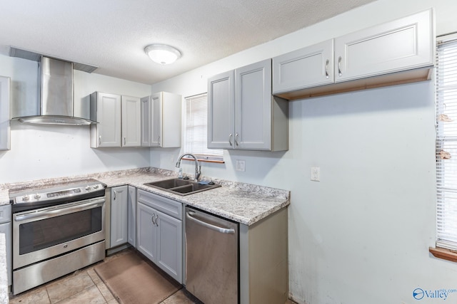 kitchen with sink, stainless steel appliances, a healthy amount of sunlight, and wall chimney range hood