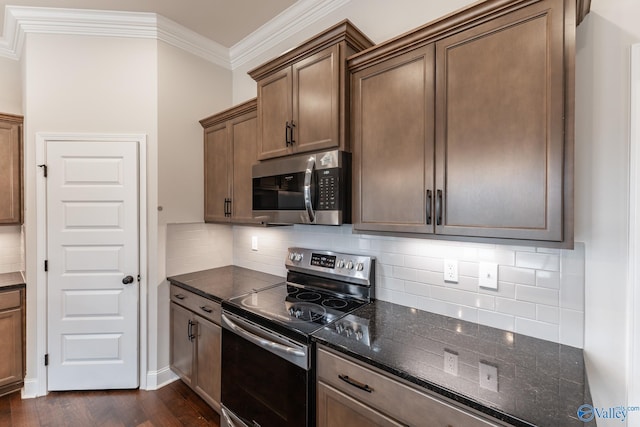 kitchen featuring ornamental molding, appliances with stainless steel finishes, dark hardwood / wood-style flooring, dark stone counters, and decorative backsplash