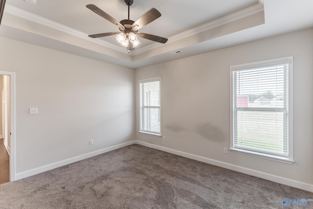 carpeted empty room with ornamental molding, a wealth of natural light, ceiling fan, and a tray ceiling