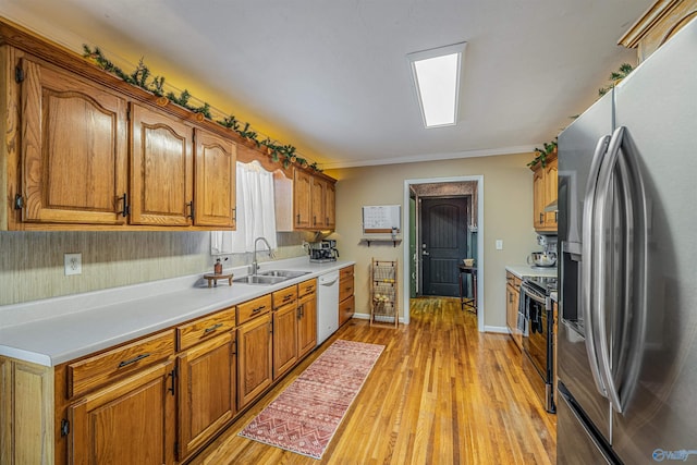 kitchen with light hardwood / wood-style floors, sink, appliances with stainless steel finishes, and crown molding