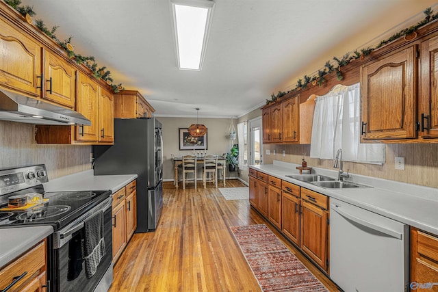 kitchen featuring decorative light fixtures, sink, light hardwood / wood-style flooring, appliances with stainless steel finishes, and ornamental molding