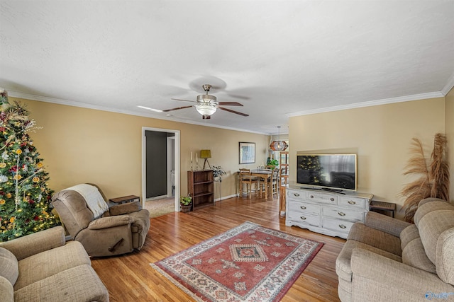 living room with ceiling fan, ornamental molding, and light wood-type flooring