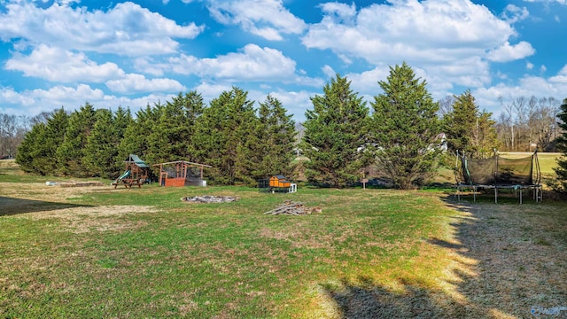 view of yard with a playground, a trampoline, and a fire pit