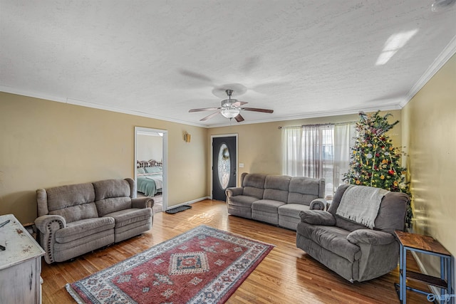 living room featuring a textured ceiling, ceiling fan, ornamental molding, and light hardwood / wood-style flooring