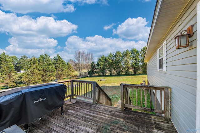 wooden deck with a trampoline, a yard, and area for grilling