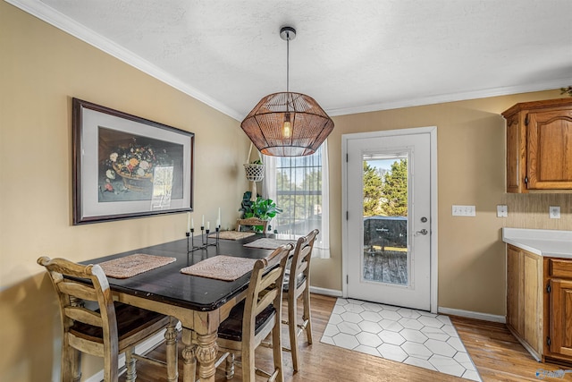 dining area with light wood-type flooring, ornamental molding, and a textured ceiling