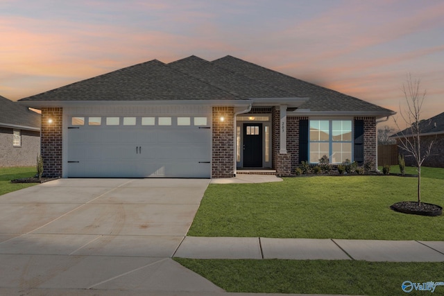 view of front of house with a shingled roof, concrete driveway, an attached garage, a front lawn, and brick siding