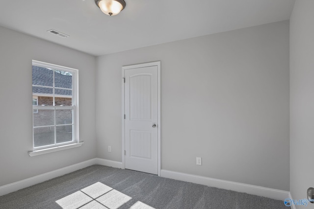 carpeted spare room featuring visible vents and baseboards