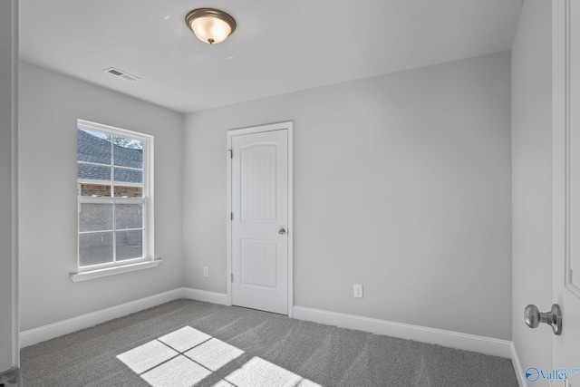 empty room with carpet floors, baseboards, and visible vents