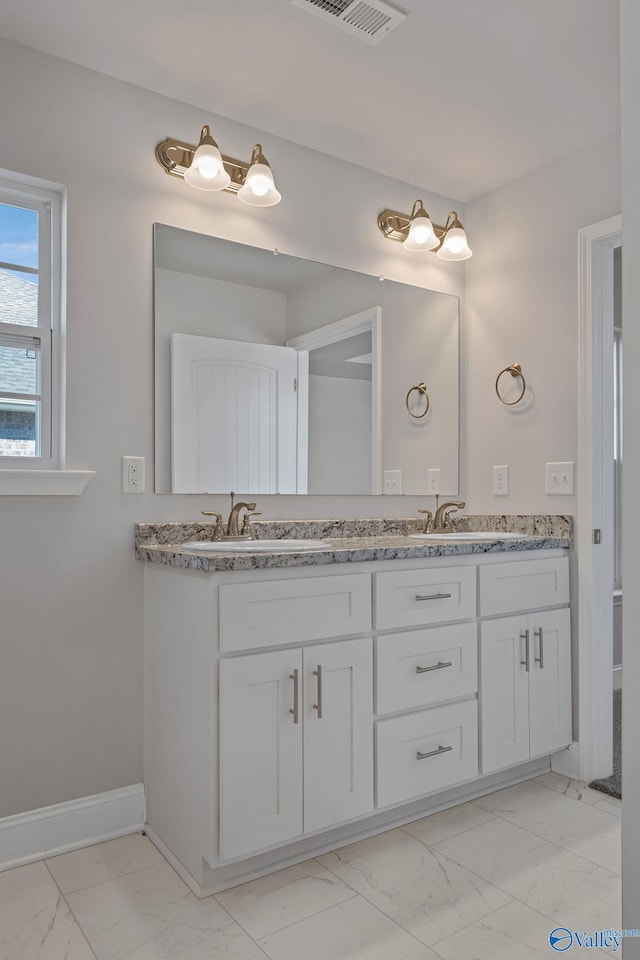 bathroom featuring marble finish floor, a sink, and double vanity