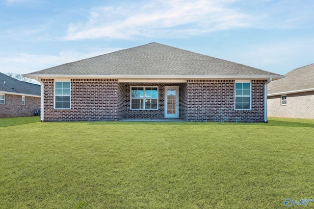 back of house featuring a yard, brick siding, and roof with shingles