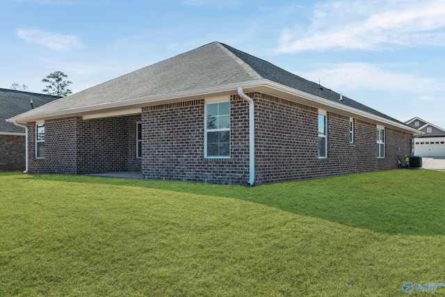 exterior space featuring brick siding, a shingled roof, cooling unit, and a yard