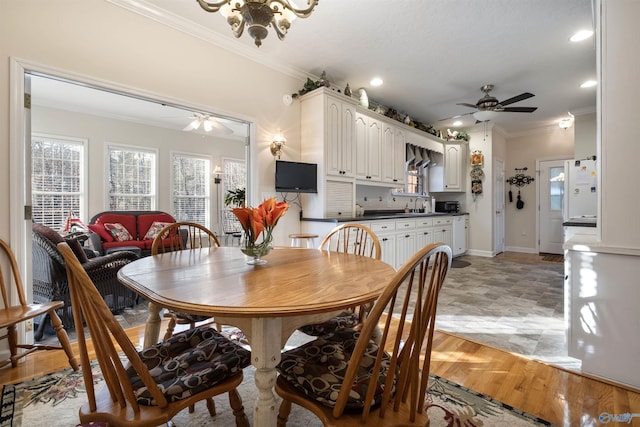 dining area with ceiling fan, ornamental molding, sink, and light hardwood / wood-style floors