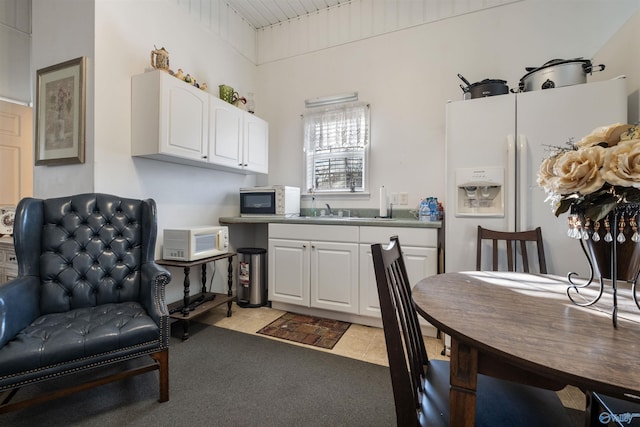 kitchen with white cabinetry, white appliances, sink, and light carpet