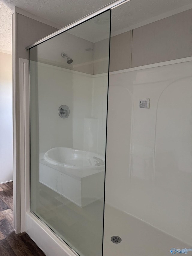 full bath with a textured ceiling, wood finished floors, and a stall shower