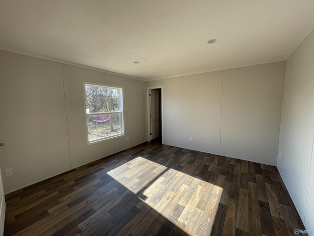 spare room featuring crown molding and dark wood finished floors