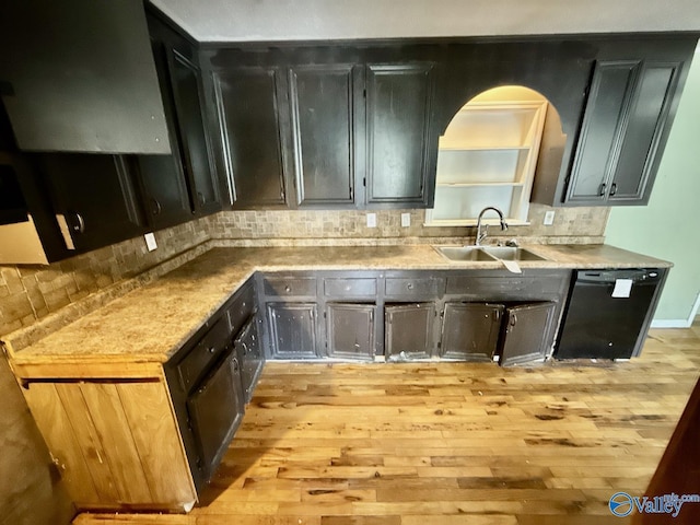 kitchen featuring black dishwasher, a sink, ventilation hood, light wood finished floors, and decorative backsplash
