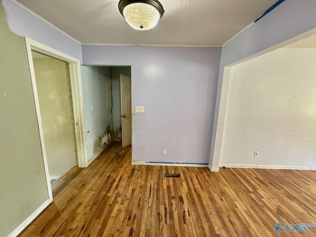 unfurnished bedroom featuring ornamental molding, baseboards, a closet, and hardwood / wood-style floors