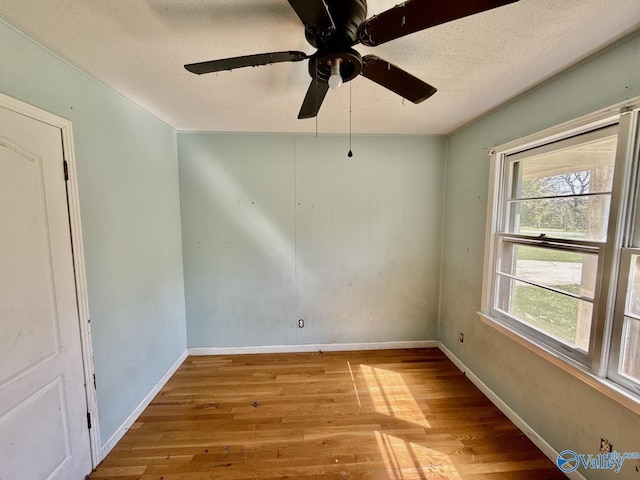 unfurnished room with wood finished floors, ceiling fan, and baseboards