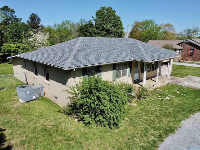 view of side of property featuring a yard, fence, brick siding, and roof with shingles