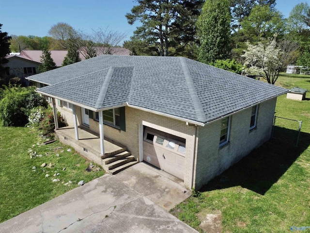 view of property exterior with driveway, brick siding, a yard, a shingled roof, and covered porch