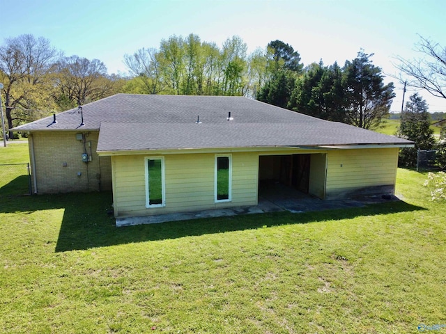 back of house featuring a shingled roof and a lawn