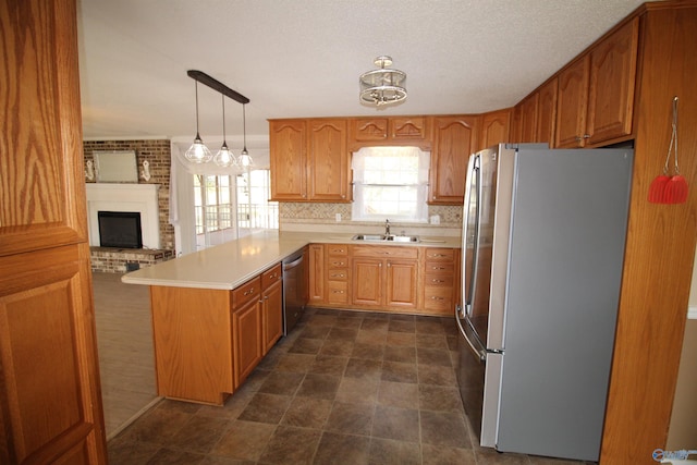 kitchen featuring kitchen peninsula, appliances with stainless steel finishes, sink, decorative light fixtures, and a fireplace