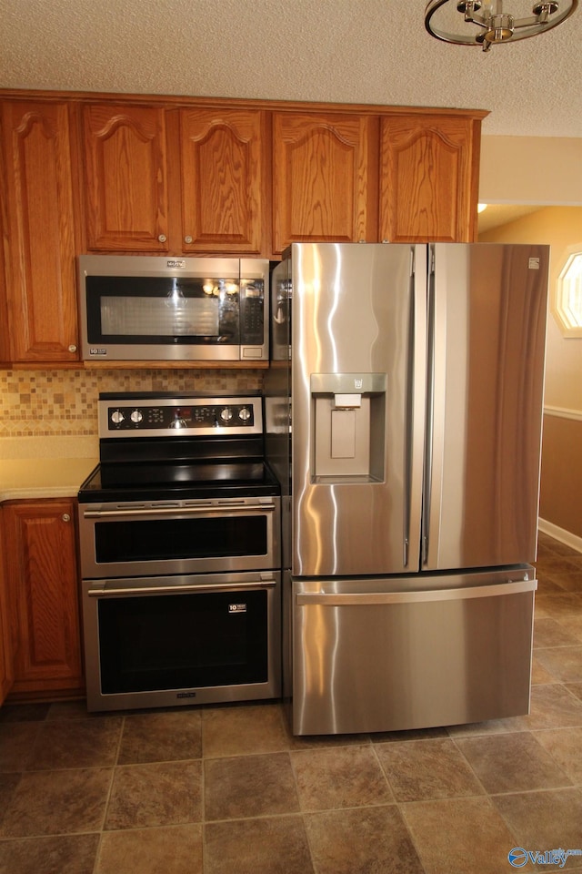 kitchen featuring stainless steel appliances, a textured ceiling, and tasteful backsplash