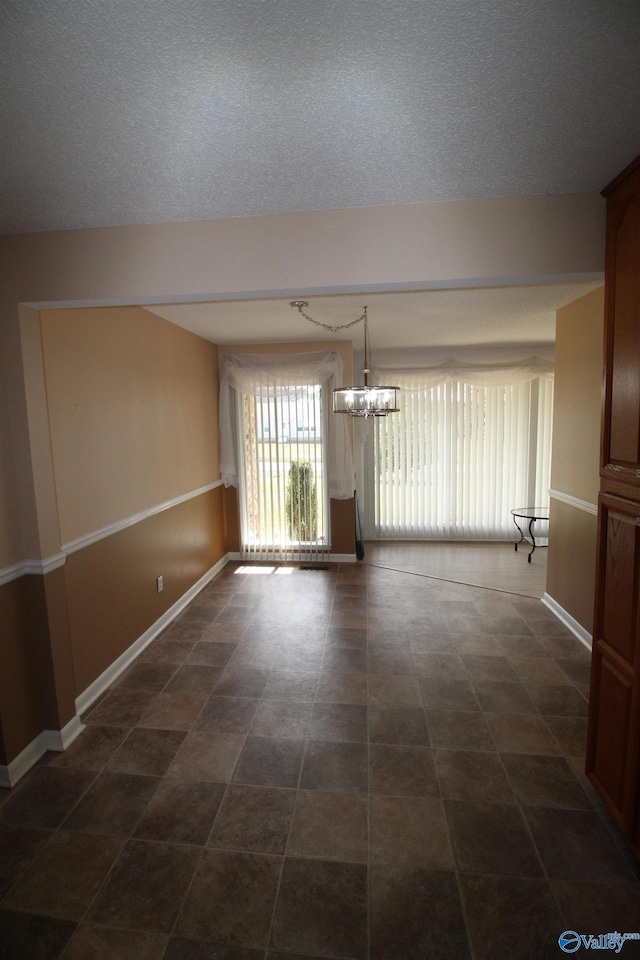 empty room with an inviting chandelier and a textured ceiling