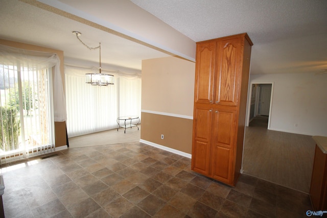 empty room with a chandelier and a textured ceiling